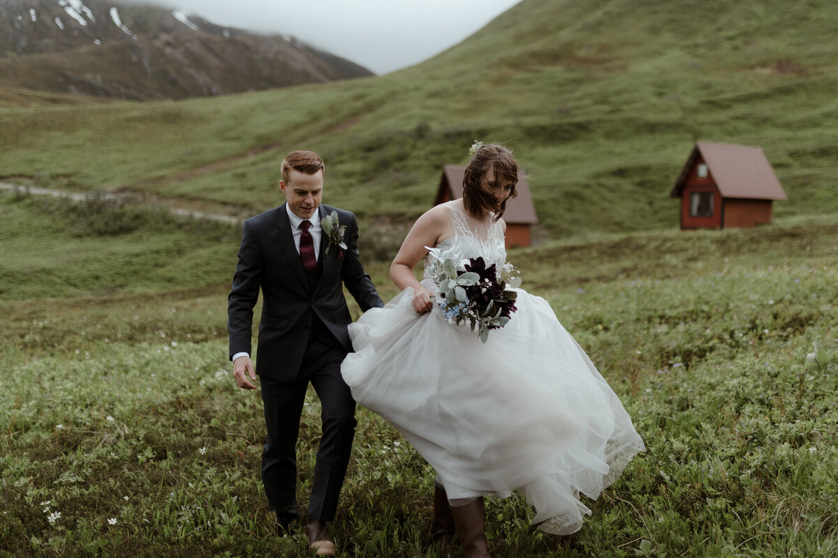 bride and groom walking up hillside