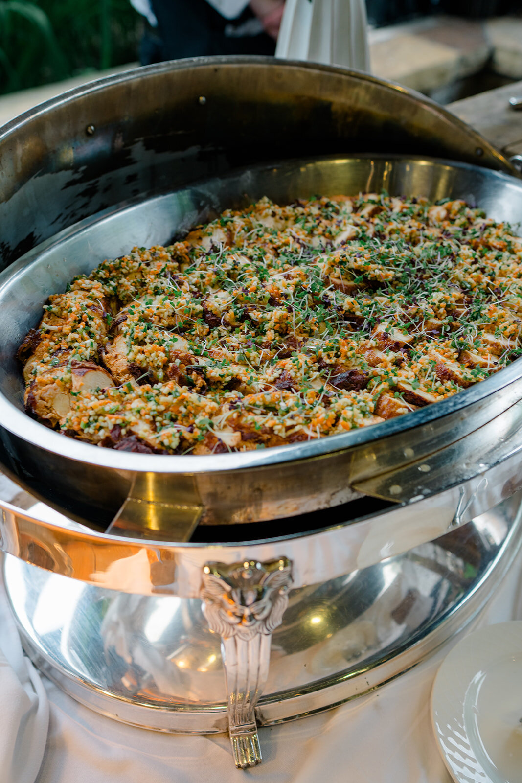 Warm catering dish with herb-crusted entrée served in a polished chafing dish at luxury wedding reception in Highlands, NC.