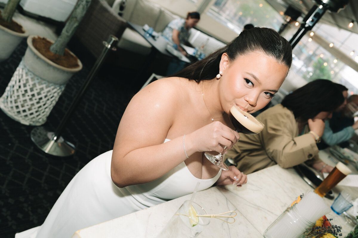 A bride sipping on her signature drink at her wedding reception