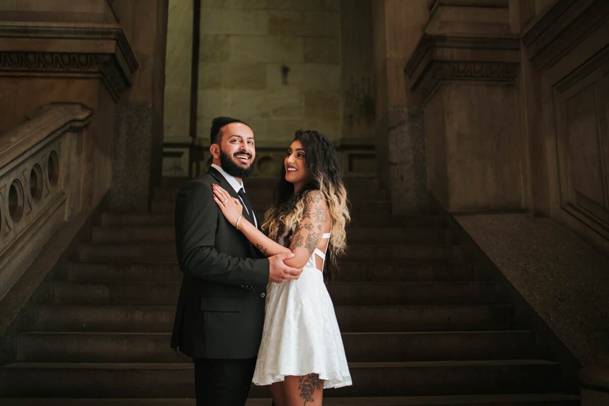 South Asian couple embracing each other and smiling on a staircase in Philadelphia.