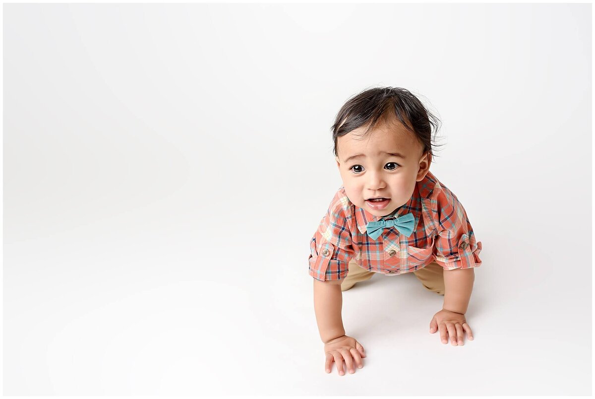 Toddler boy crawling  and smiling on white floor