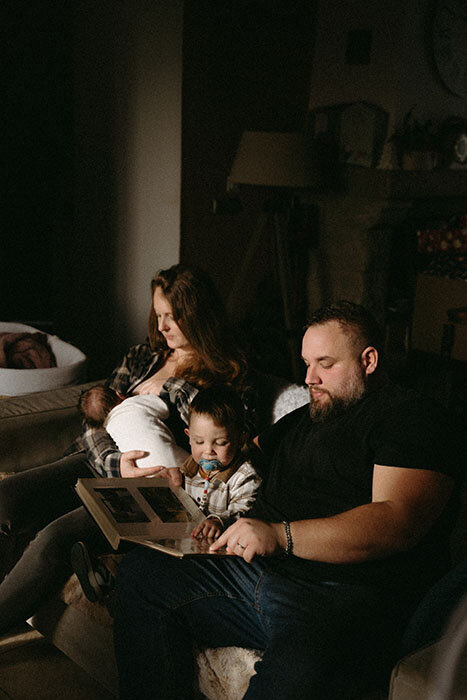 Parents dans leur canapé entourés de leur enfants pour une séance photo famille à la maison.