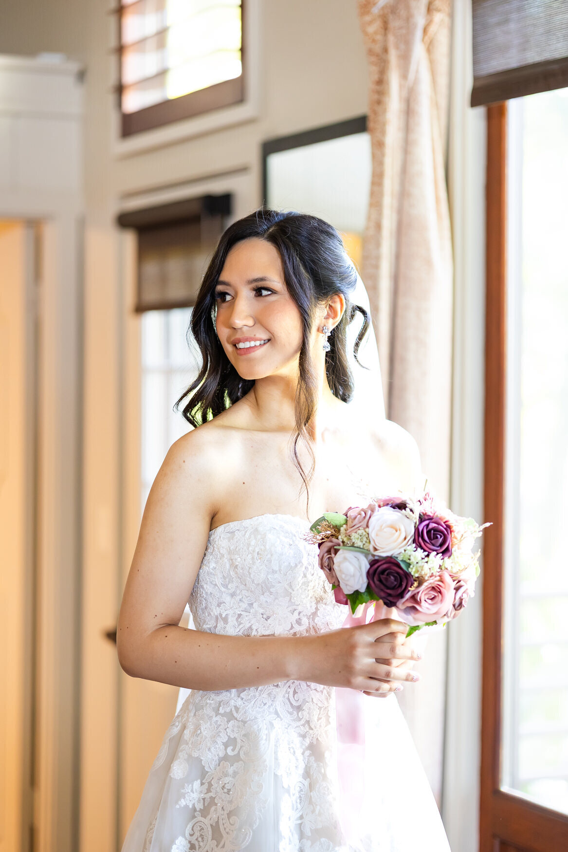 bride gazing off to the side holdign ehr bouquet in bridal suite