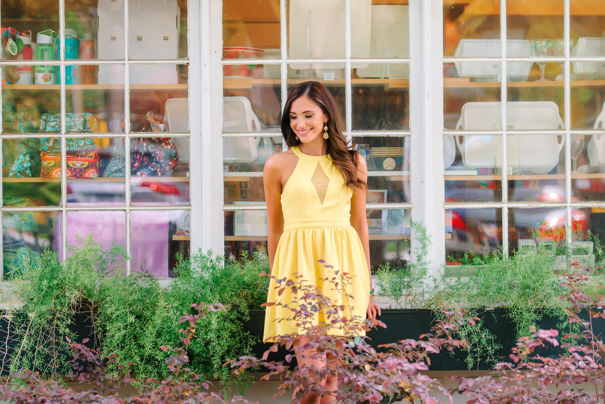 Teen girl smiling in yellow dress during senior portraits at Charleston’s historic market district

