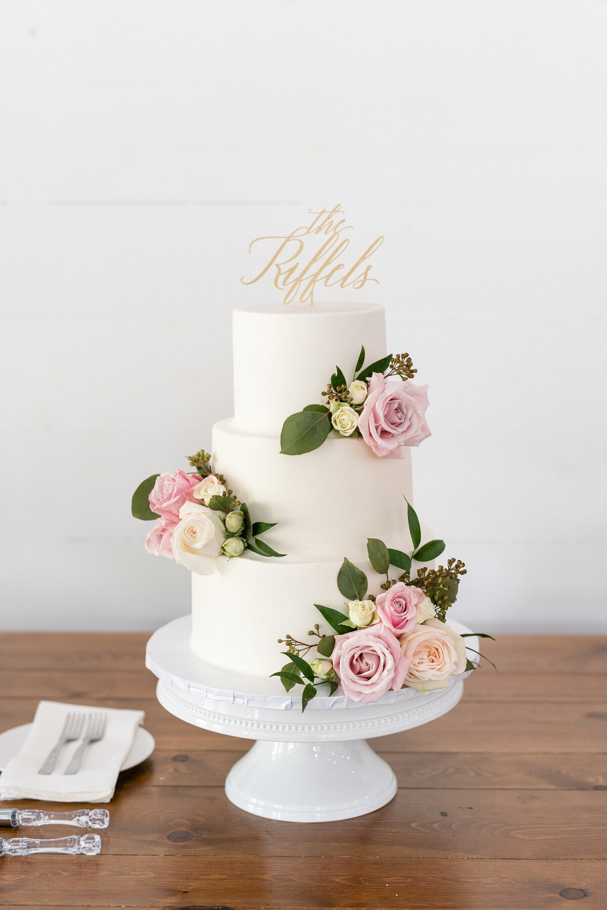 White with pink flowers and greenery on wedding cake