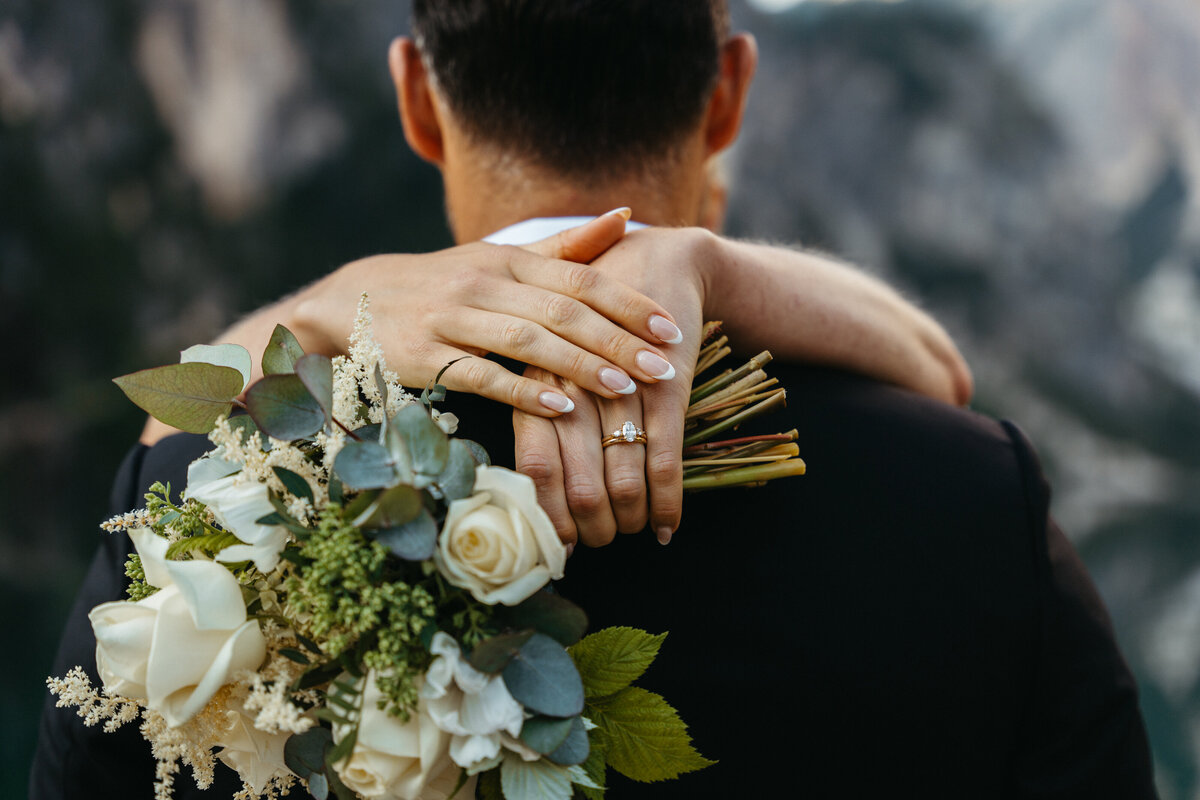 Couple holding bouquet during intimate embrace at Lago di Braies