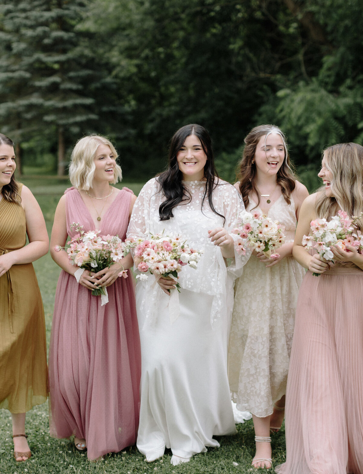 bride, bridesmaids laugh in pink and warm tones, different bridesmaids dreses