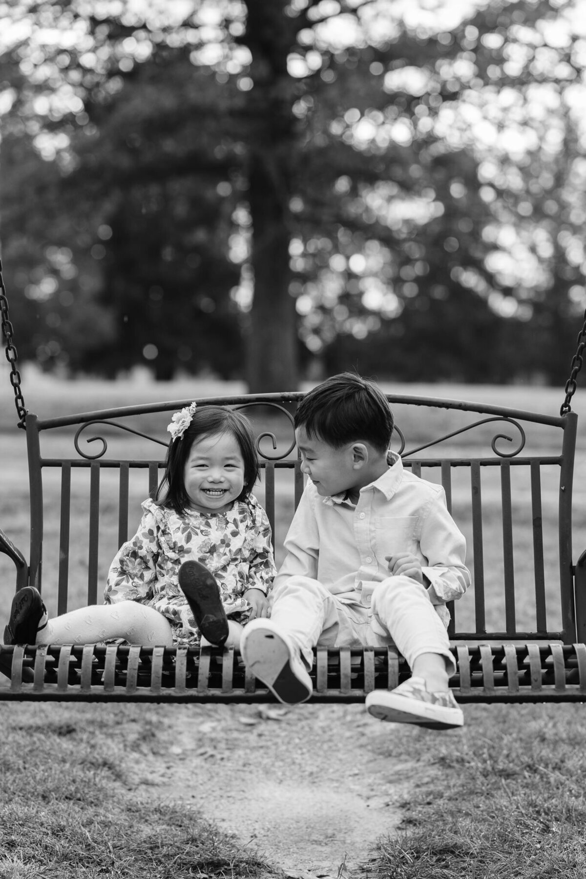 B&w candid moment of a brother looking lovingly at his giggling sister, captured by Denise Van