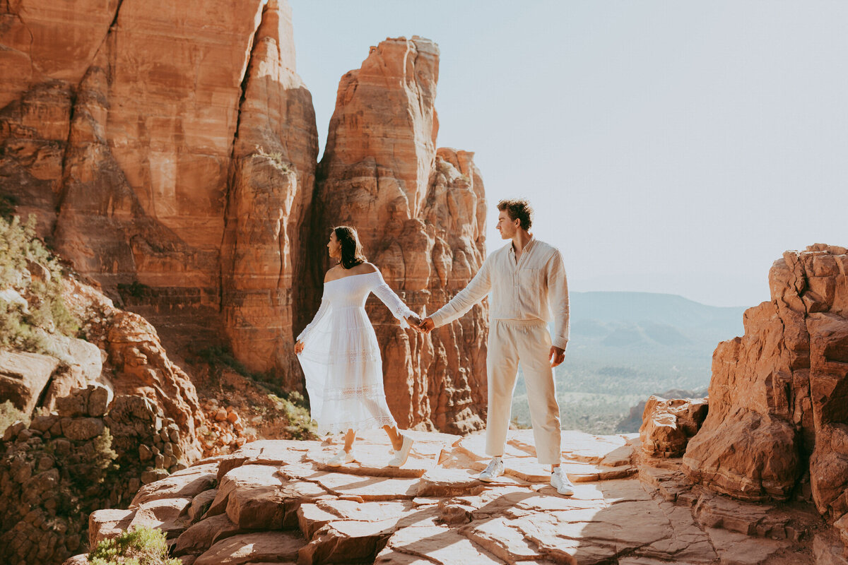 couple stands on cliff edge for engagement photos