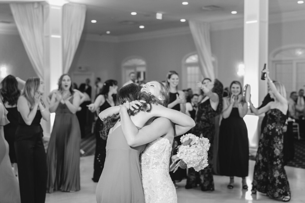 A bride hugs the winner of the bouquet toss who happens to be her sister