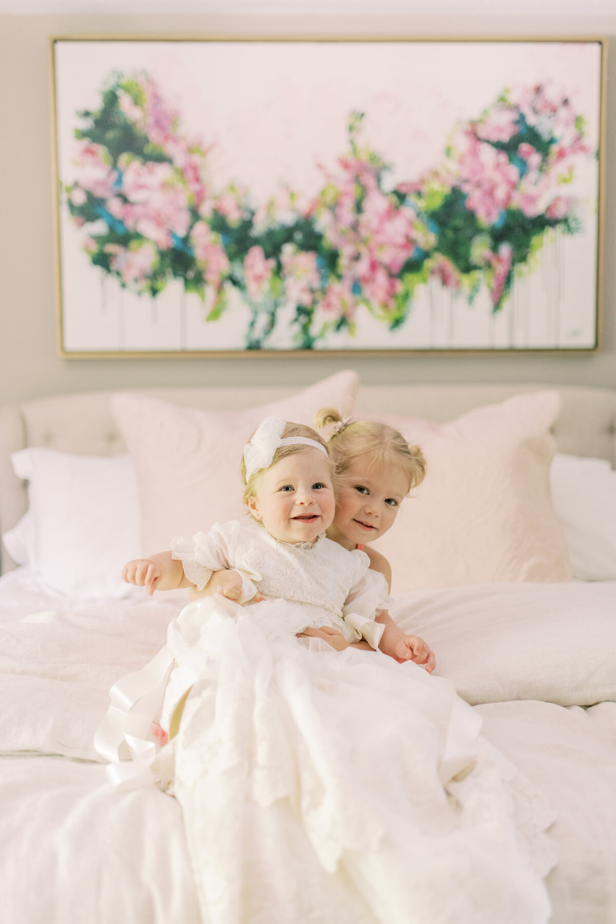 Big sister embraces baby again, cherishing the memory of baptism day with warmth and wonder.
