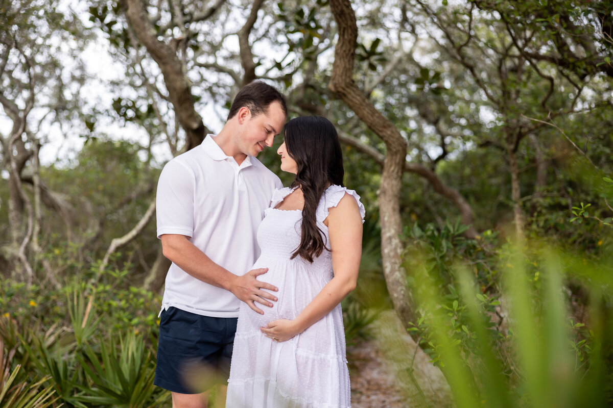 happy couple with pregnant wife  enjoying a beach photoshoot in Grayton Beach State Park, Florida  by 30A photographer Gwyne Gray.
