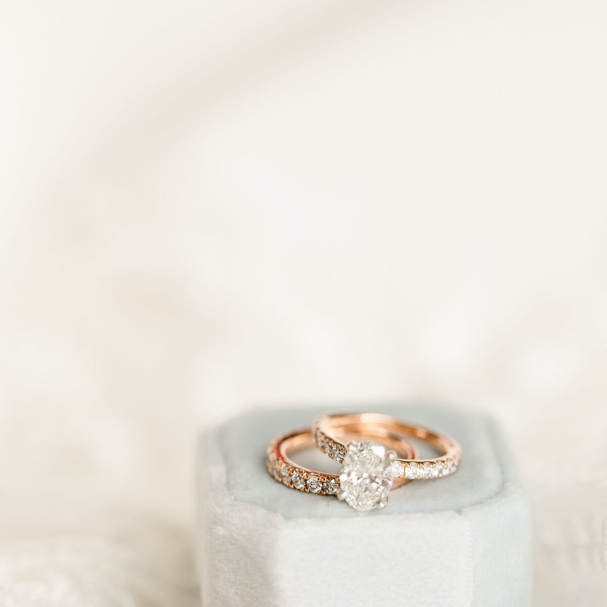 Rose gold engagement ring set are  photographed on top of a duty blue ring box
