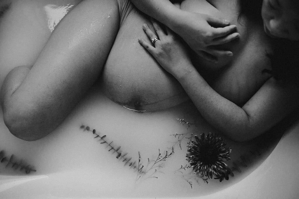 black and white image pregnant woman laying in bath tub
