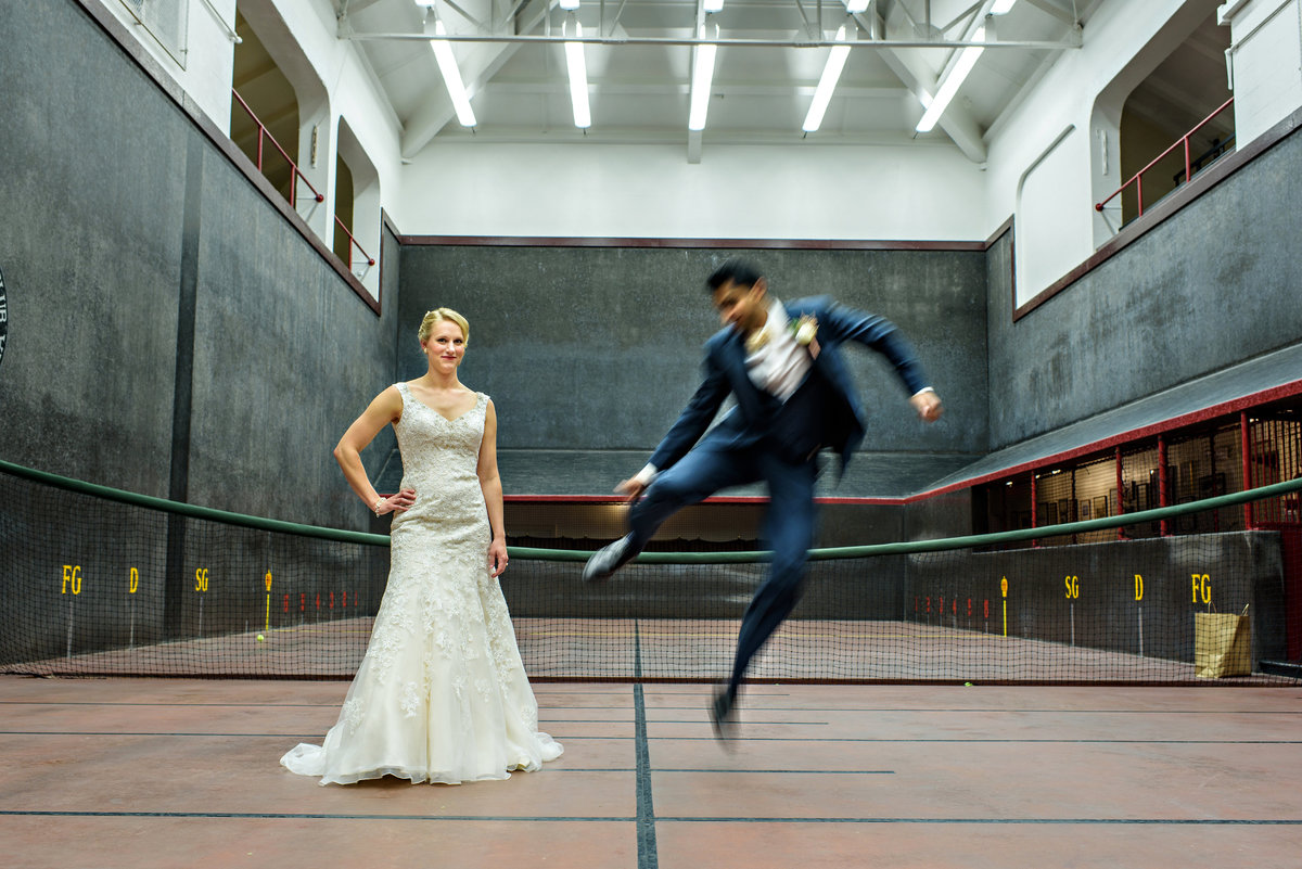 A bride watches her groom jump through the air on the tennis court in Philadelphia before the wedding.