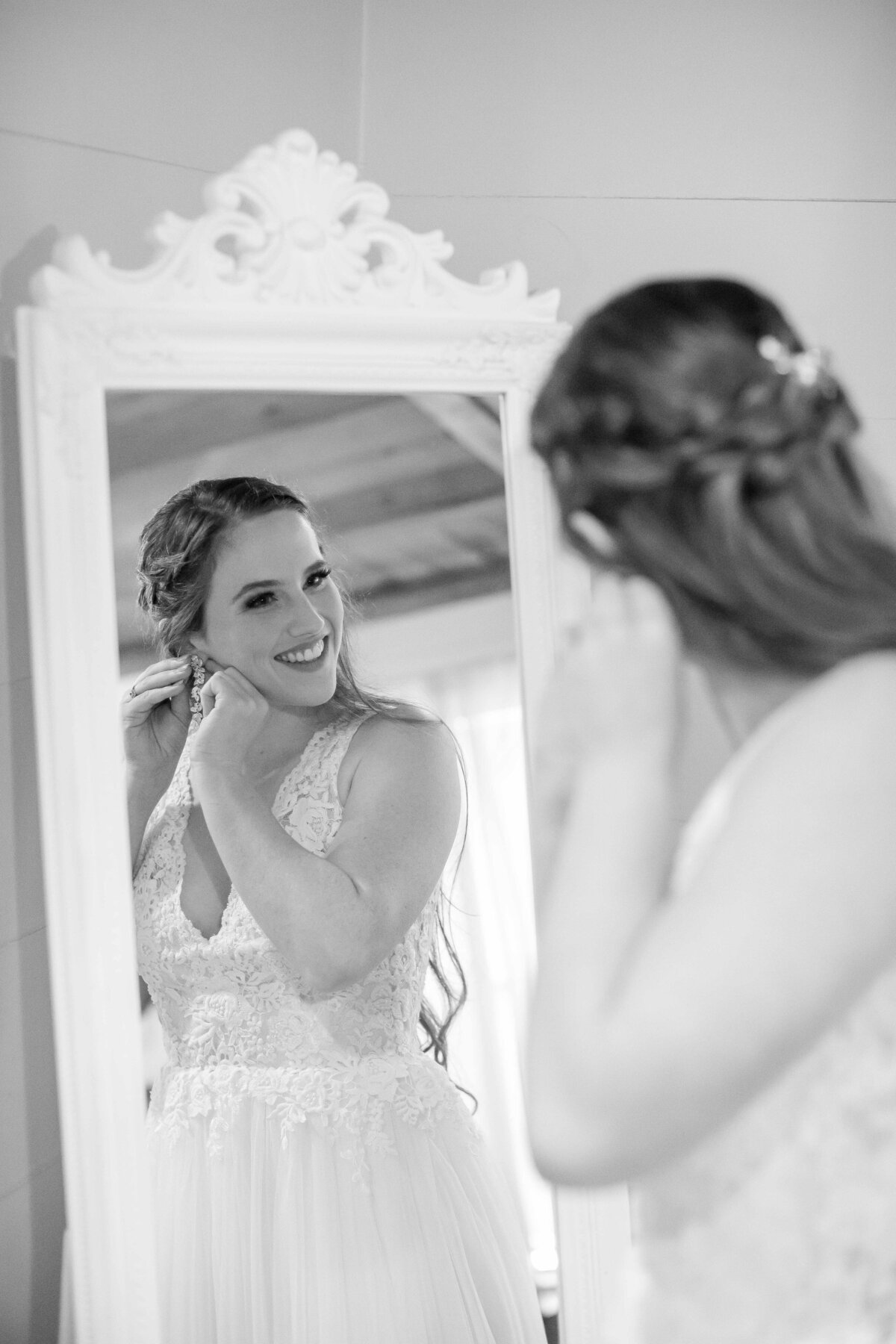 bride in black and white puts on earrings with mirror at Milltown wedding New Braunfels Texas