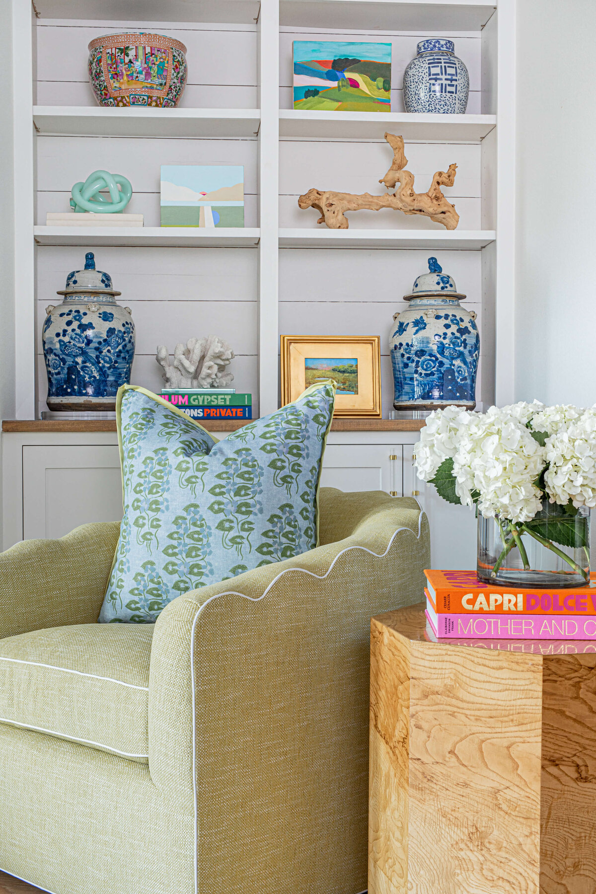 oyster creek studios aryns home light green chair with blue patterned pillow and china vases on bookshelf