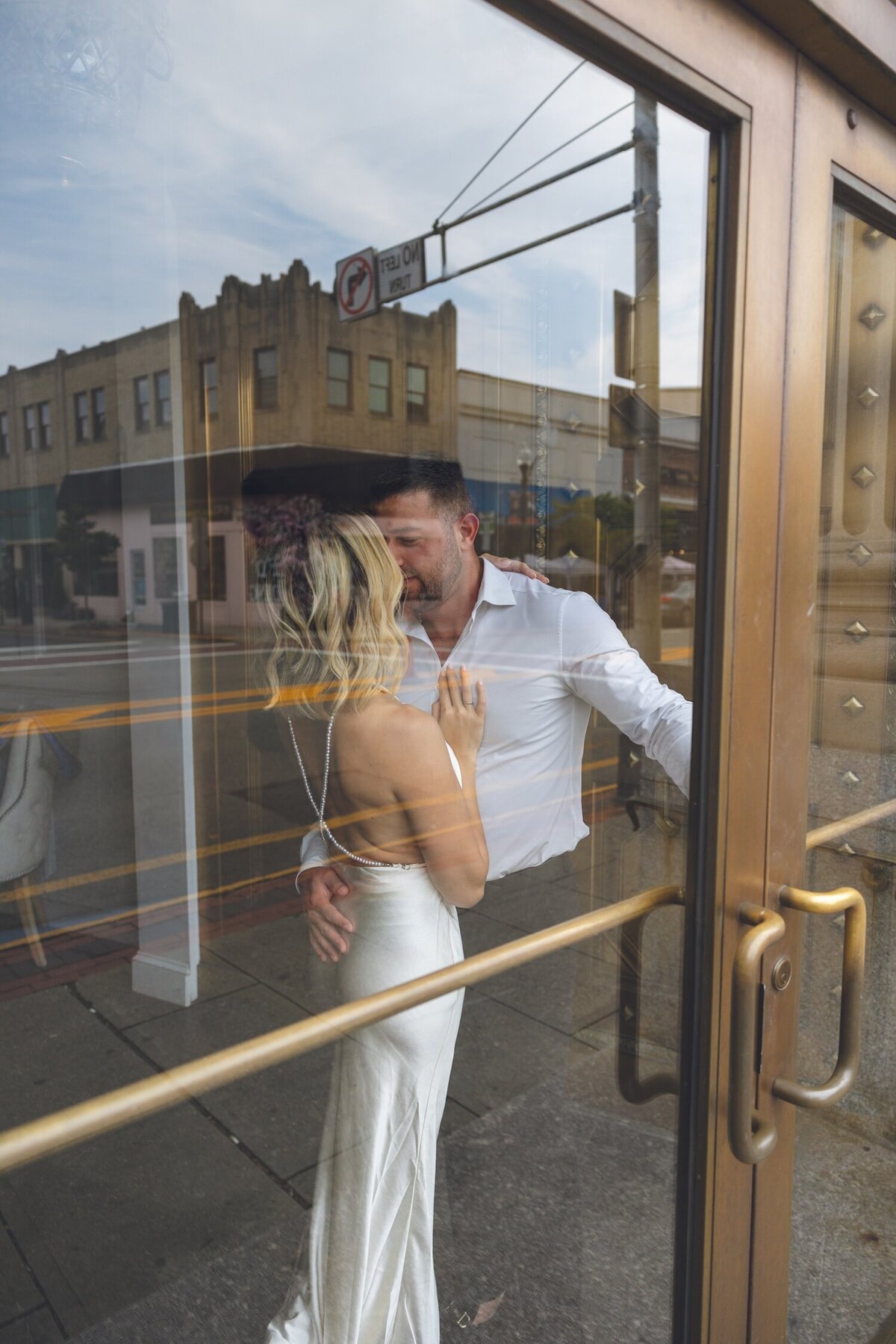 Bride and groom laughing together by the glass doors at Felina.