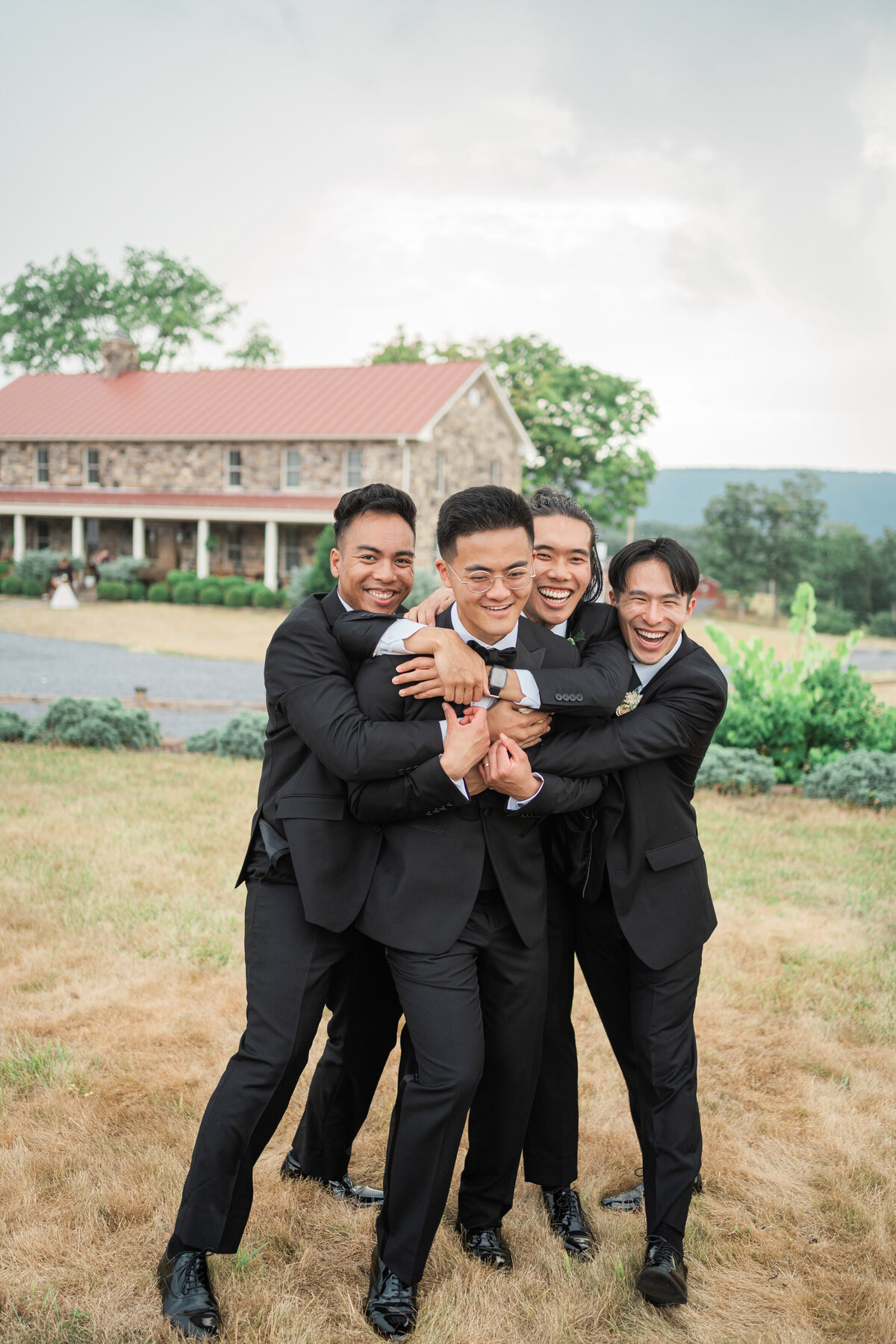 Friends hugging a groom as they all smile