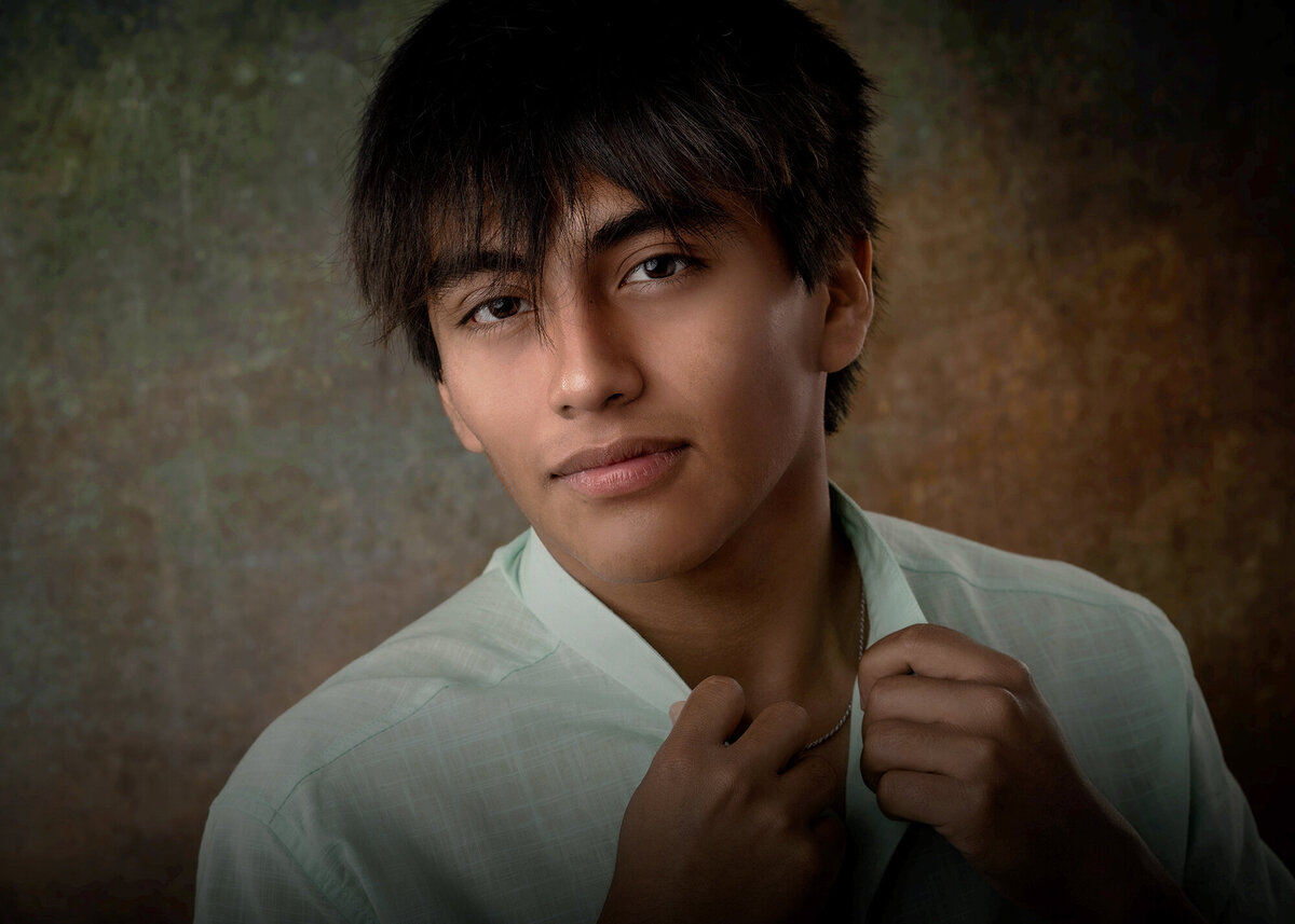 A close up taken by a Pella Senior Photographer of a high school senior holding his shirt collar in a studio