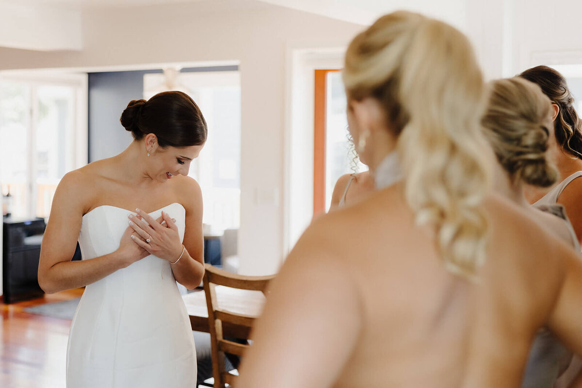 Bride looking at her dress whilst bridesmaid look on