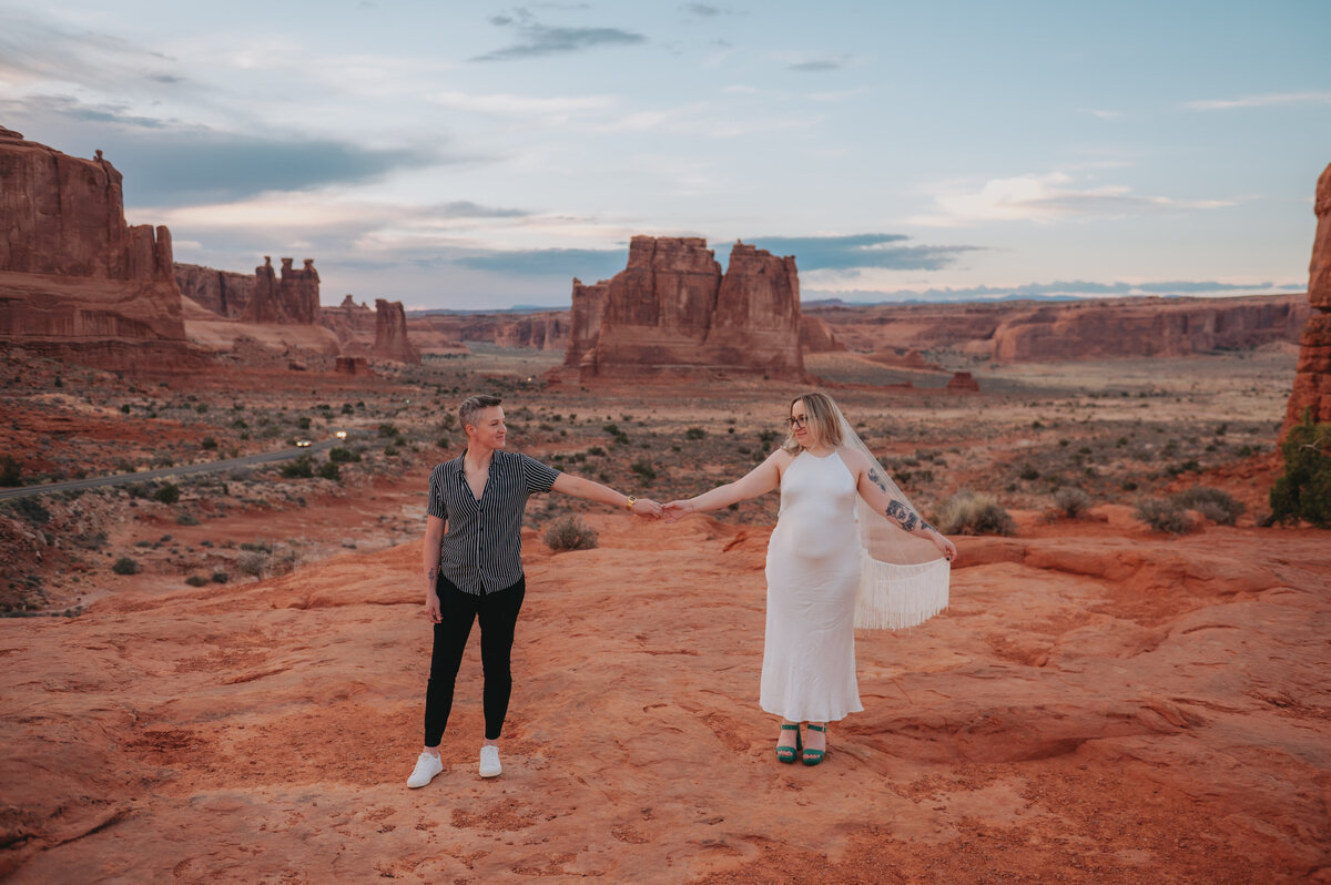 A couple holds hands in Arches National Park
