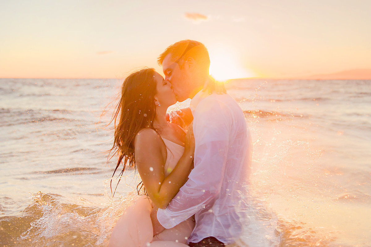 Golden toned image of couple kissing in the ocean just before the sunsets on Maui