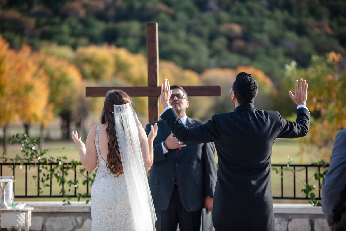 bride and groom raise  their hands during praise and worship songs at Sendera Springs wedding
