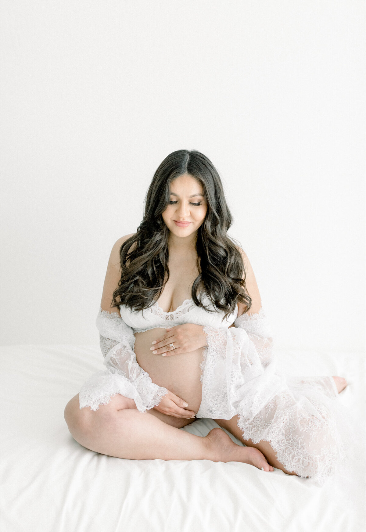 Expecting mother in a tulle gown holding her belly