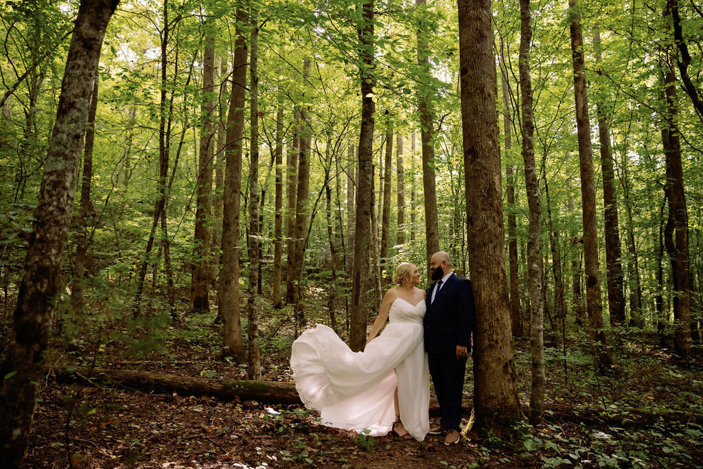 woodland elopement at Greenbrier with couple standing in a grove of tall trees with the brides gown flowing upward