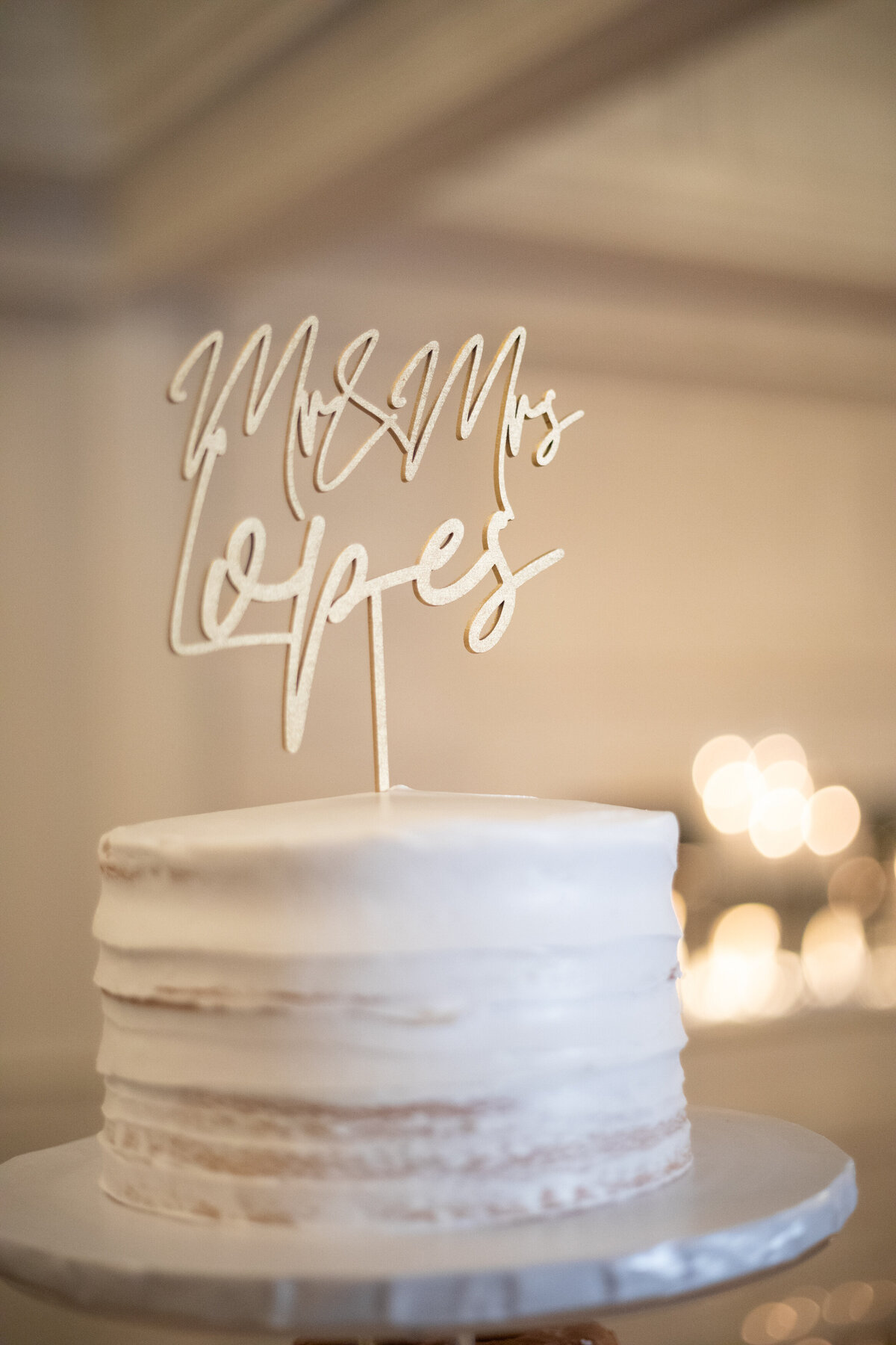 Close up of single tier wedding cake with "Mr. & Mrs. Lopes" sign
