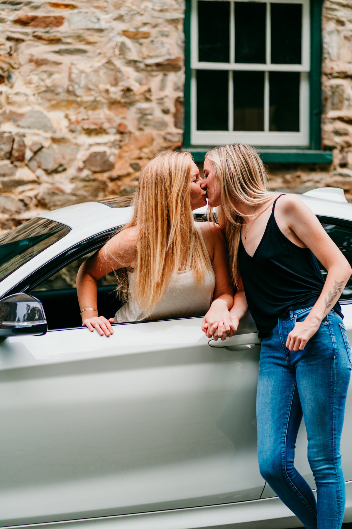 Couple leaning against a car and sharing a kiss