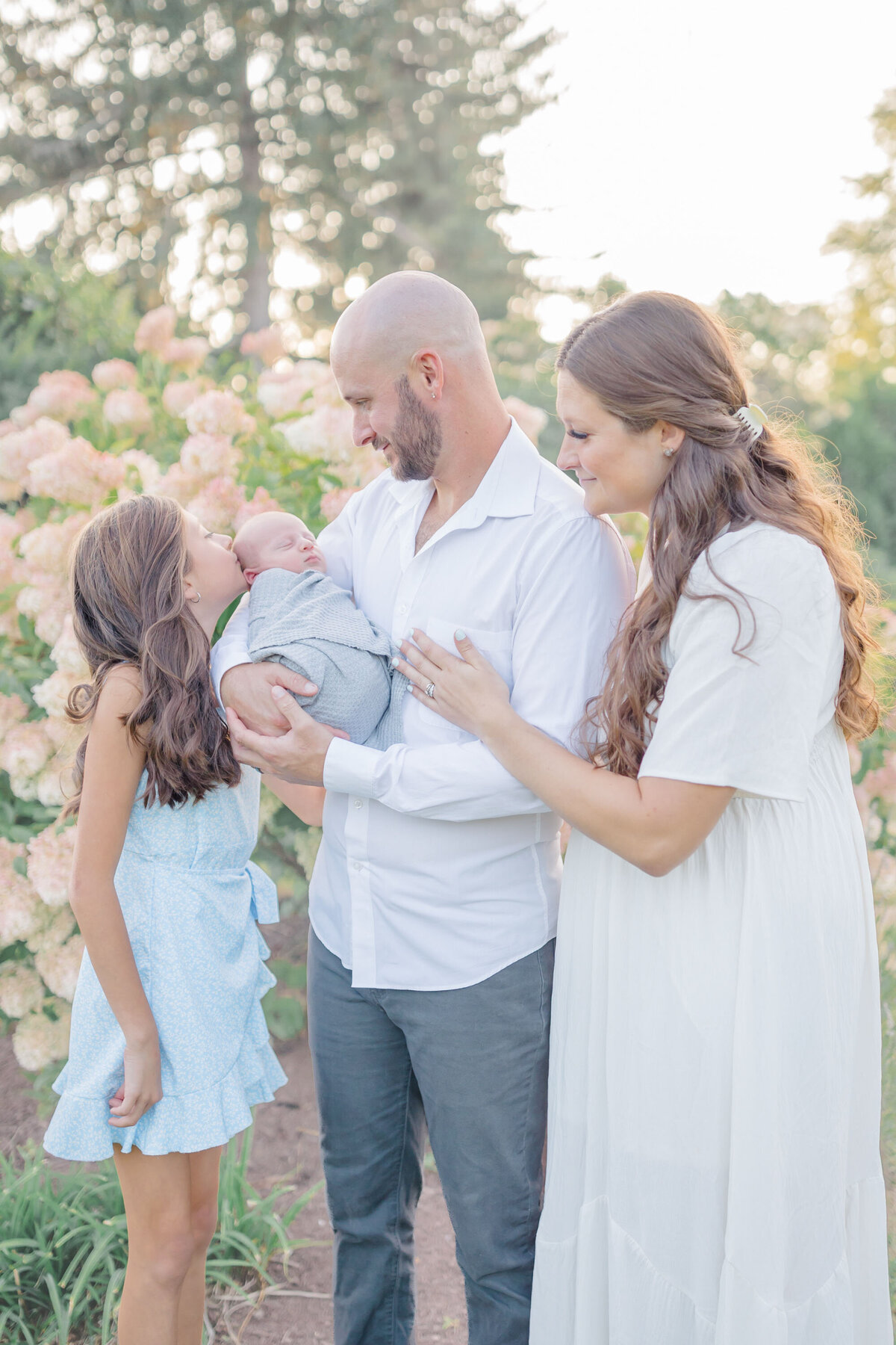 now a family of four, mom dad and sister look on at the newest addition to their family