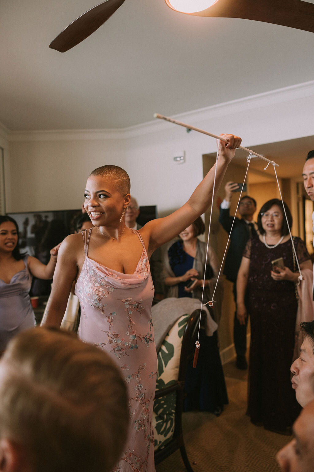Chinese wedding game bridesmaid holding stick with food on it for groomsmen to eat