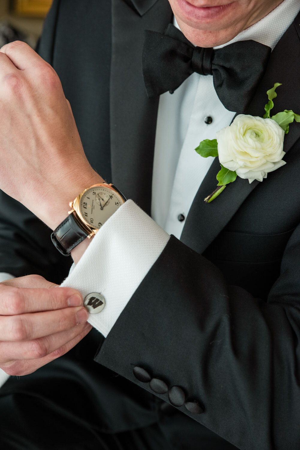A man in a tuxedo with a watch on his wrist