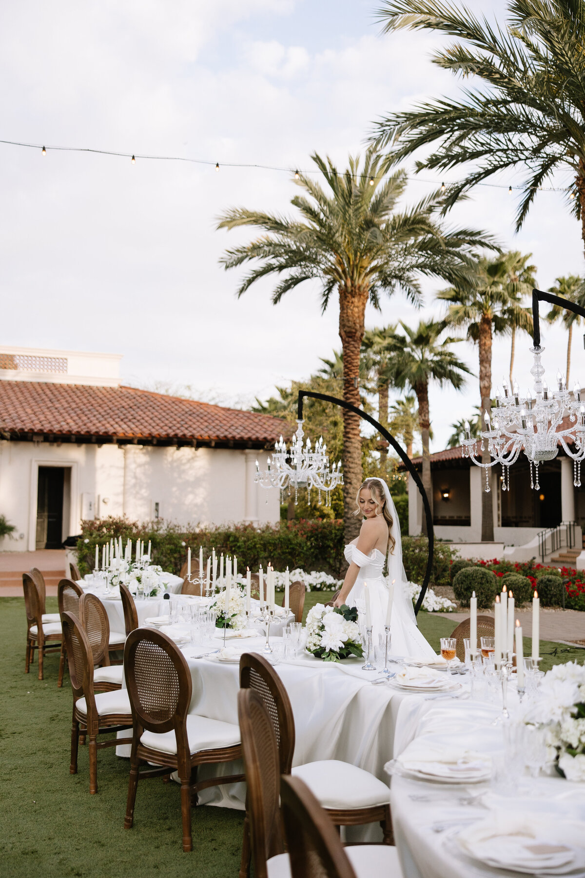 elegant outdoor wedding reception with crystal chandeliers, classic serpentine tablescape, and bride in off-shoulder gown