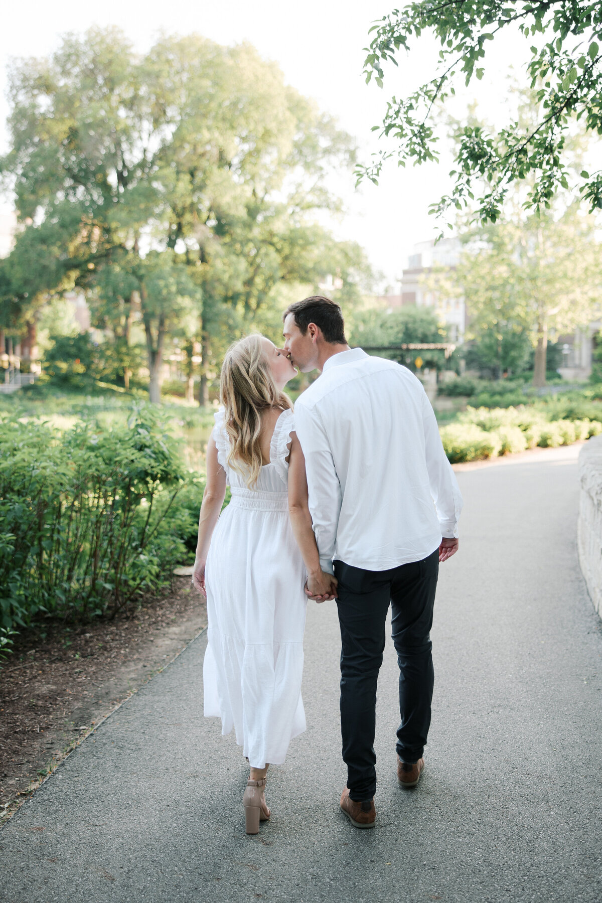 Engaged couple kisses on shaded path in Columbus, taken by Philly wedding photographer.
