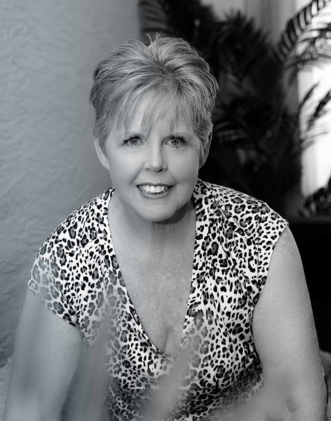 An older woman in a leopard print shirt poses during her boudoir photoshoot.