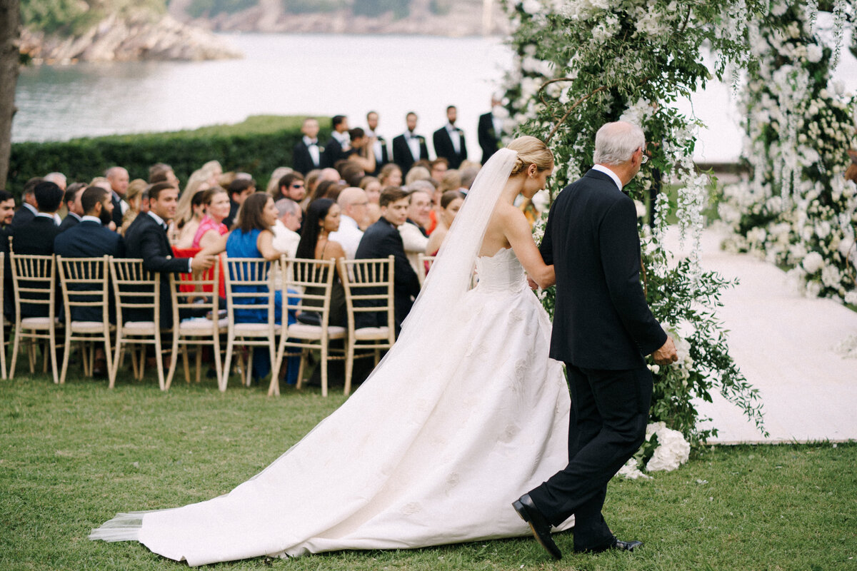 Bride walking down the aisle with her father at an elegant outdoor ceremony near the water, captured by a wedding photographer in Toronto