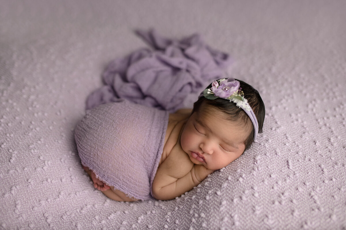 newborn baby girl on purple background