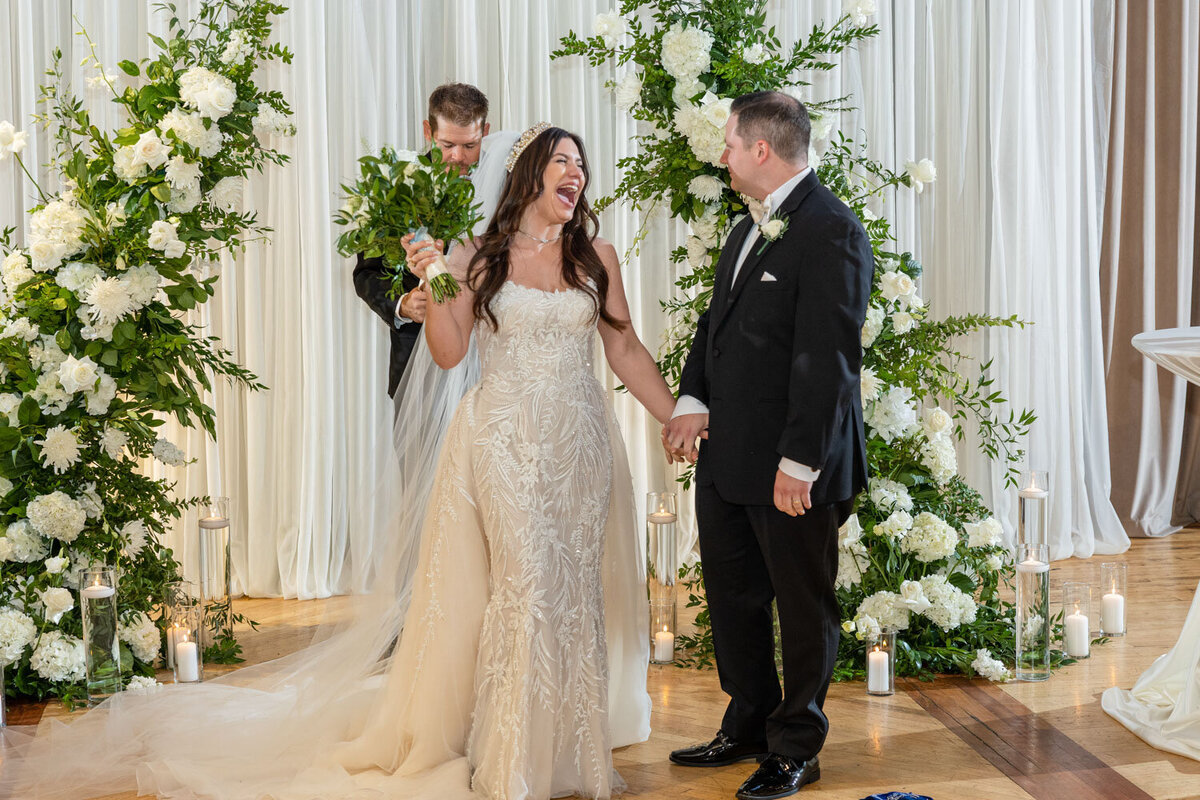 A bride and groom are holding hands at their wedding ceremony.