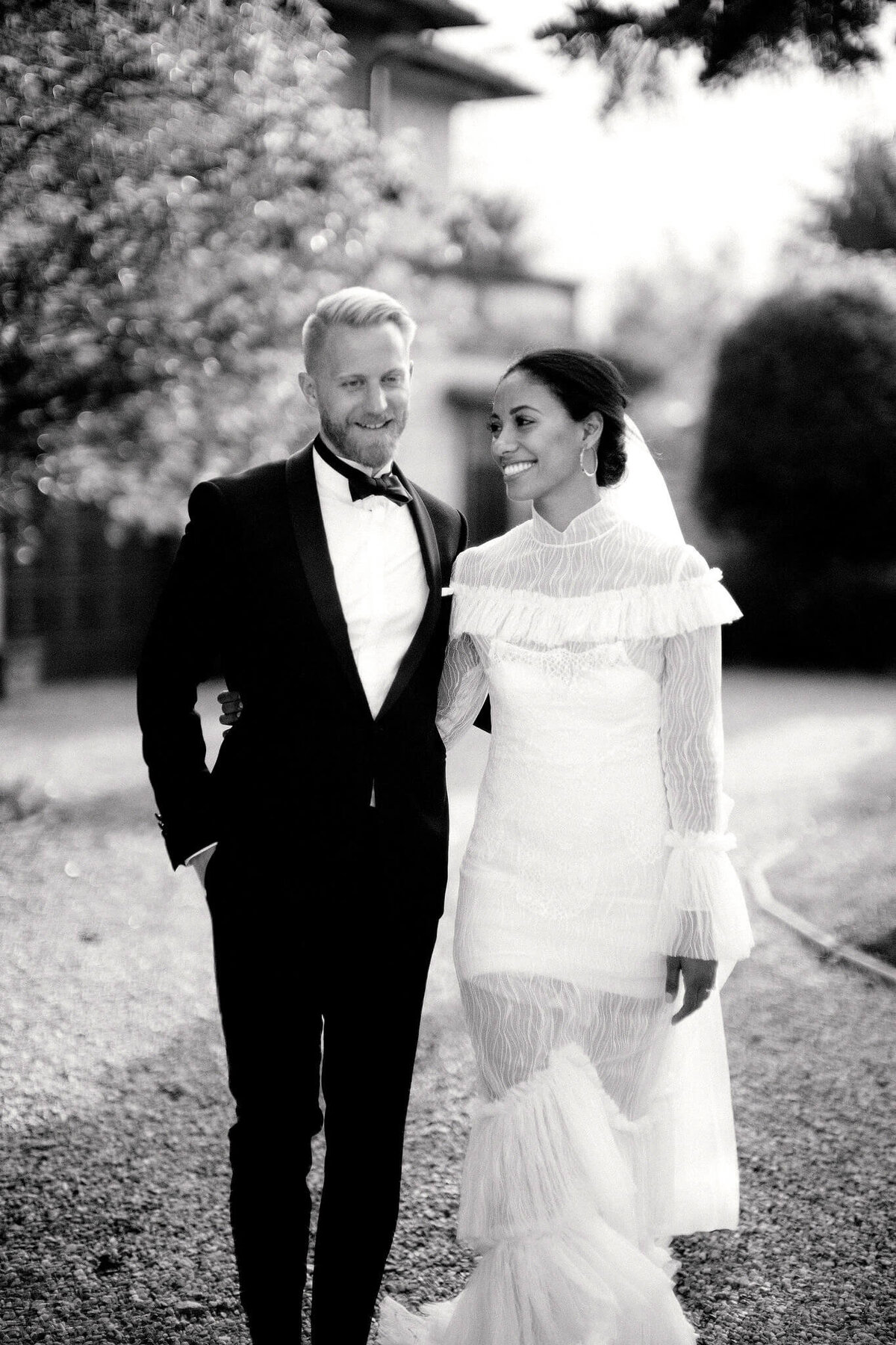 The bride and groom are happily walking in a garden.