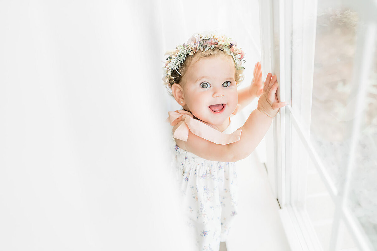 a little girls standing in front of a white window professionally photographed by a destin family photographer.