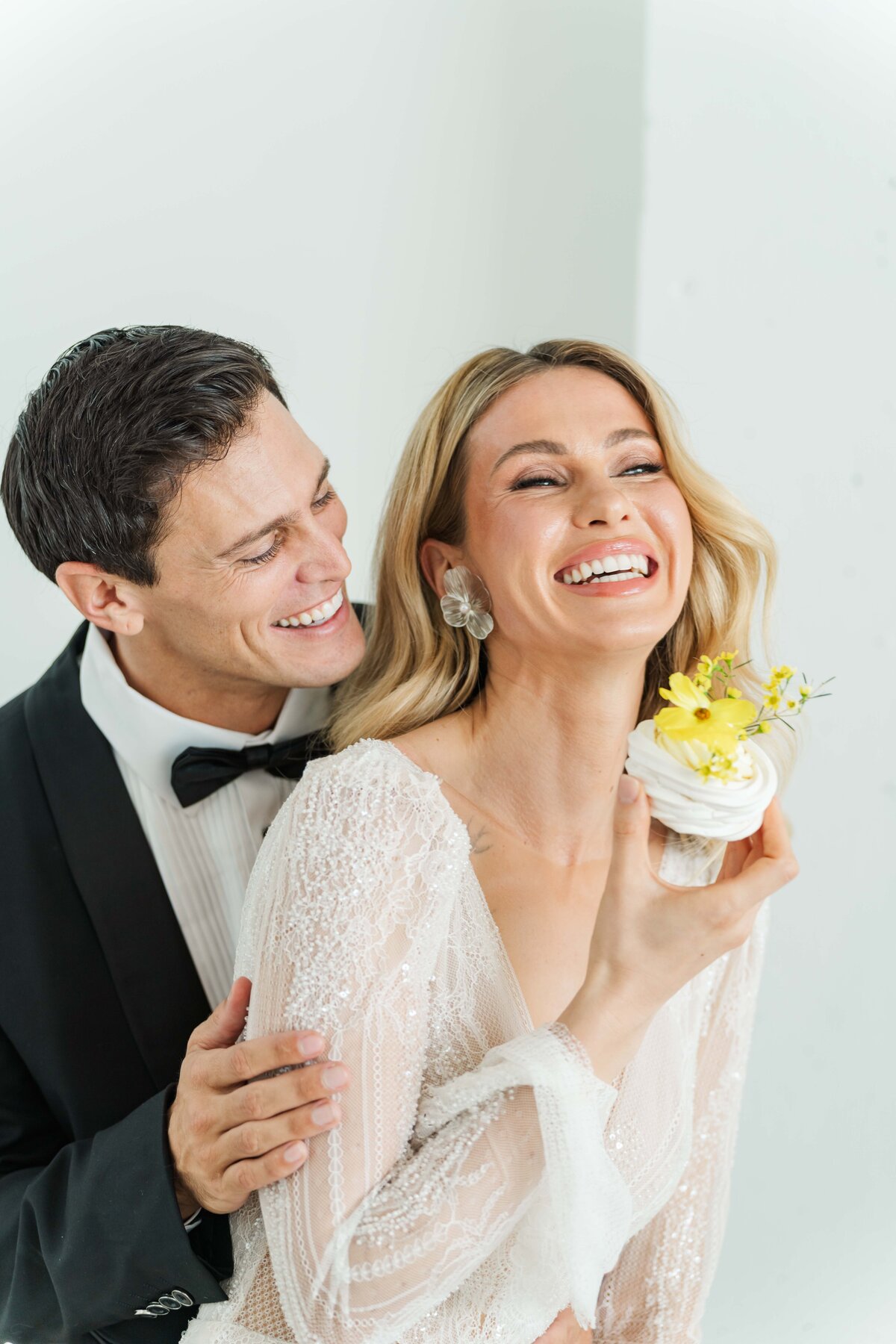 bride and groom holding a cuo cake while smiling