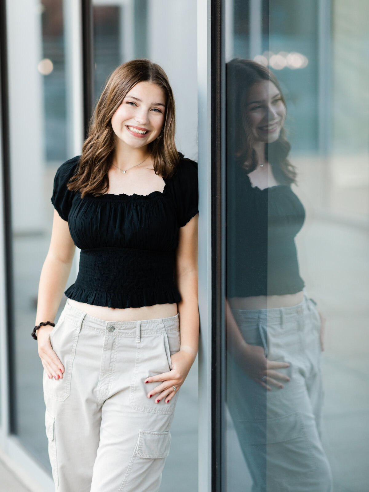 senior girl in black shirt leaning against window for senior photos in cleveland 