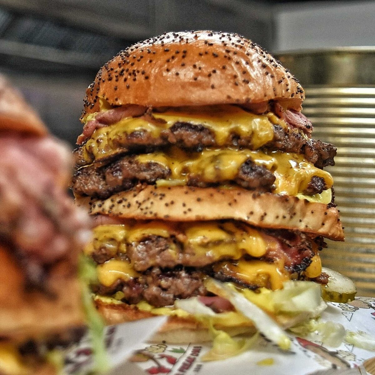Huge burger with four patties of beef and oozing out cheese sauce and lettuce