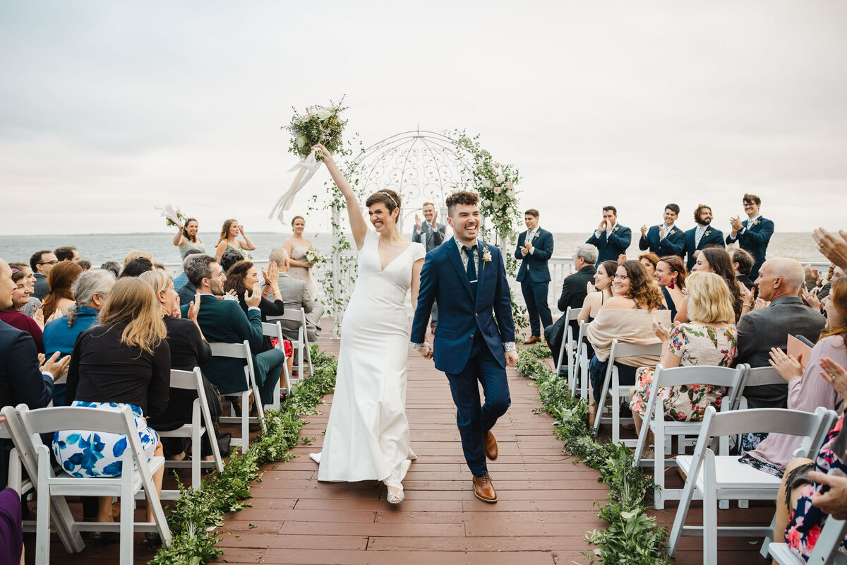 A newlywed couple holding hands and walking back up the aisle after getting married