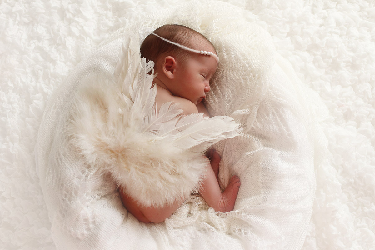 Newborn baby sleeping in her angel wings at home photo session in Calgary Alberta