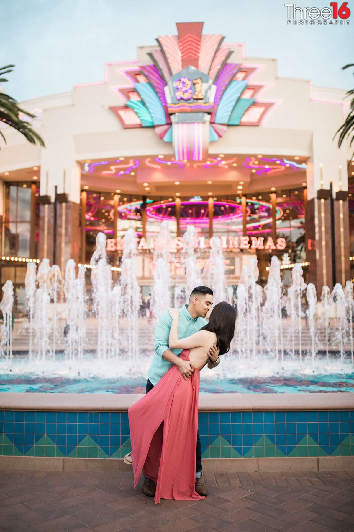 Groom to be dips and kisses his fiance in front of the water fountain at the Irvine Spectrum