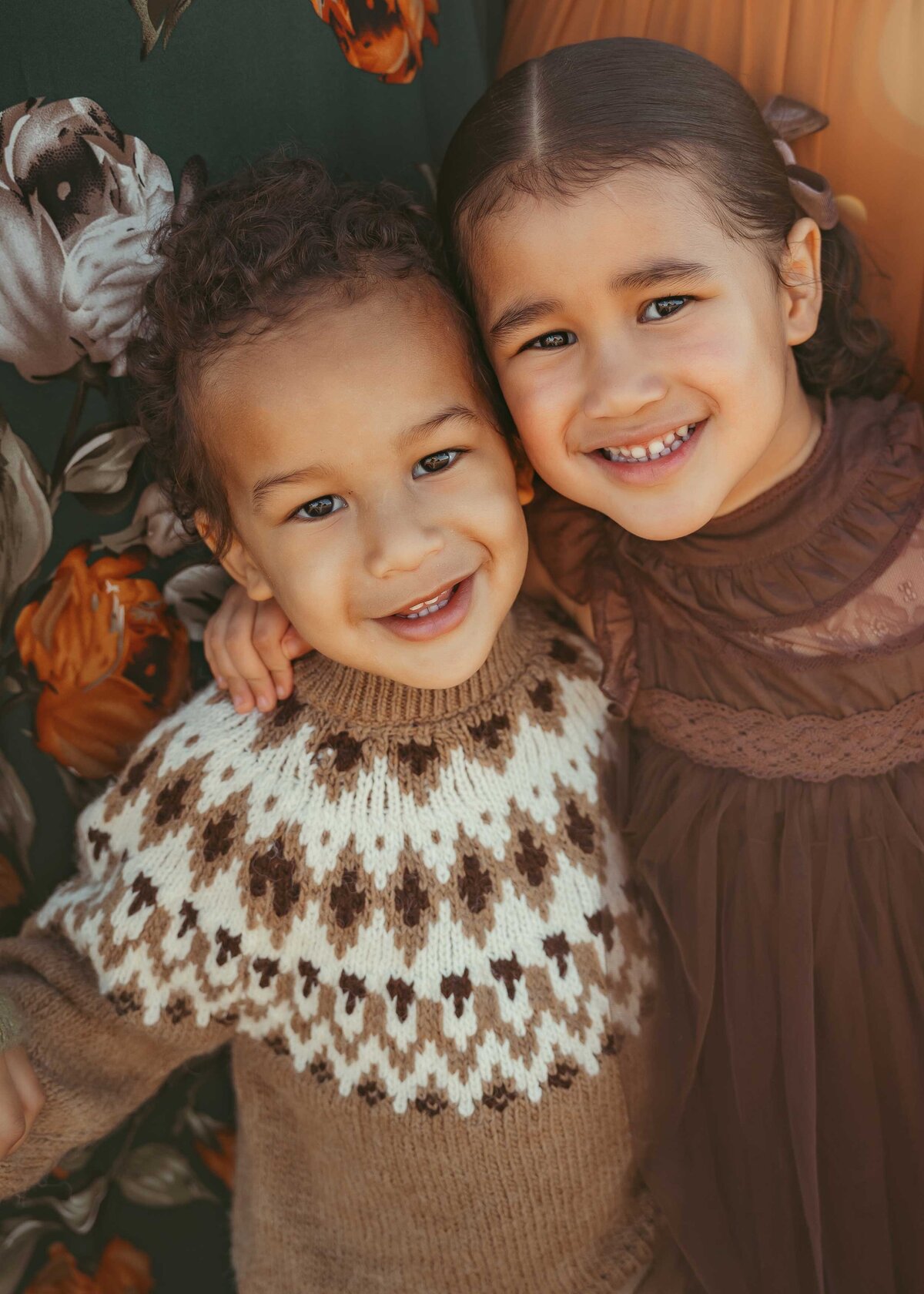 Young brother and sister side by side smiling and wearing cozy fall outfits